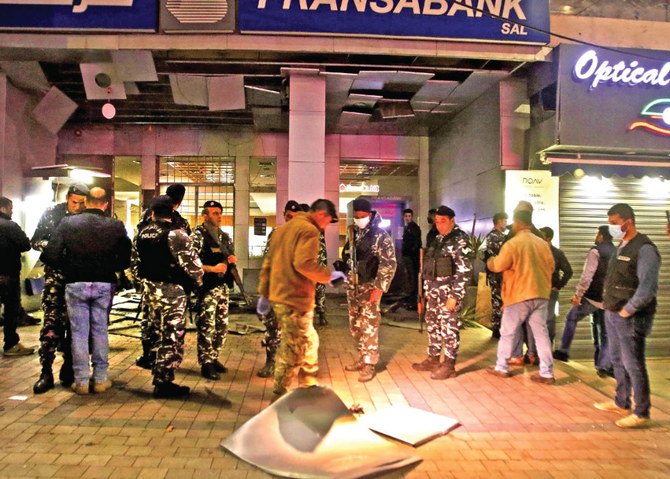 Lebanese security forces inspect the area near the Fransabank branch in Sidon after assailants targeted the bank’s entrance with an explosive device. (AFP)