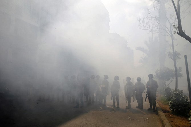 Lebanese army soldiers run in front of a Credit Libanais Bank that was set on fire by anti-government protesters, in the northern city of Tripoli, Lebanon, Tuesday, April 28, 2020. Hundreds of angry Lebanese took part Tuesday in the funeral of a young man killed in riots overnight in the northern city of Tripoli that were triggered by the crash of Lebanon's national currency that sent food prices soaring. (AP)