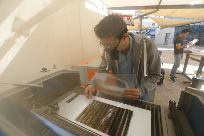 An engineer prepares cut plastic sheets before being assembled onto the crowns of protective face shields, to be used by medical professionals treating COVID-19 coronavirus patients, at the Giza Systems Education Foundation in the New Cairo suburb east of the Egyptian capital on April 8, 2020. (AFP)