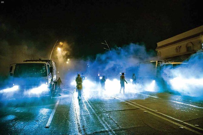 Municipal workers in the Eastern Province spray disinfectant on a street to prevent the spread of the coronavirus disease (COVID-19). (SPA)