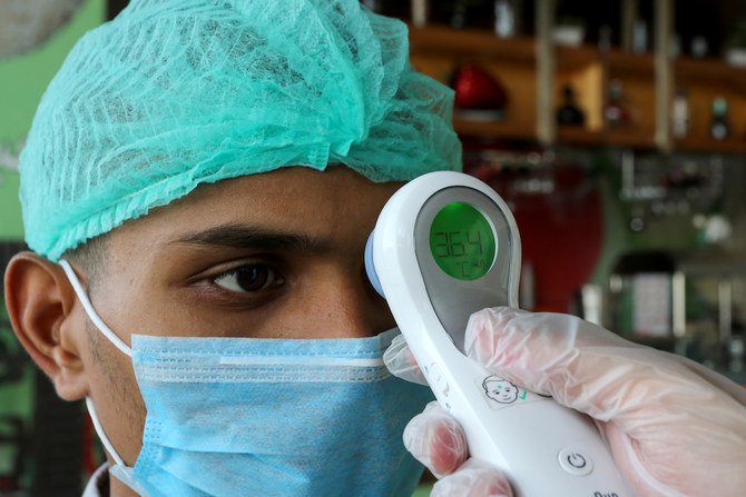 A manager wearing protective gloves checks the temperature of a worker following the outbreak of the coronavirus disease (COVID-19) upon his arrival to the restaurant, in Riyadh, Saudi Arabia, April 26, 2020. (Reuters)