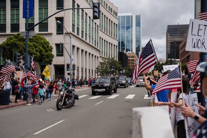 Cars and motorcycles drive through to show support for protesters rallying in downtown San Diego against California's stay at home order to prevent the spread of the novel coronavirus, which causes COVID-19, on April 18, 2020. (AFP)