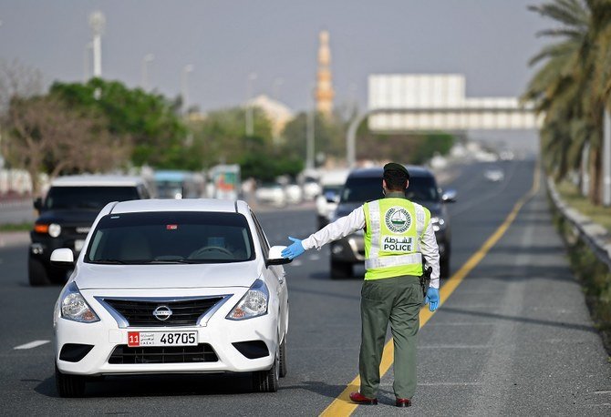 A policeman stops vehicles at a security checkpoint to examine passengers for exit permits, as people are only allowed essential travel due to a lockdown imposed by the UAE government as a measure during the COVID-19 coronavirus pandemic. (File/AFP)