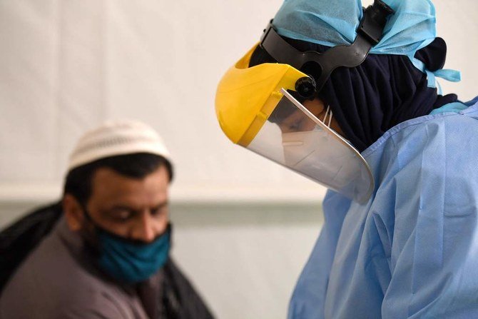 A health worker takes samples from foreign workers to check for the novel coronavirus at a testing centre in the Al Quaz area of Dubai, in the United Arab Emirates, on April 18, 2020. (AFP)