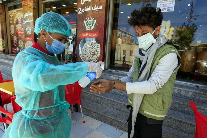 A worker wearing protective clothing sprays hand sanitiser on a customer's hand before he enters a restaurant in the Yemeni capital Sanaa on March 24, 2020 amid the COVID-19 coronavirus pandemic. (File/AFP)