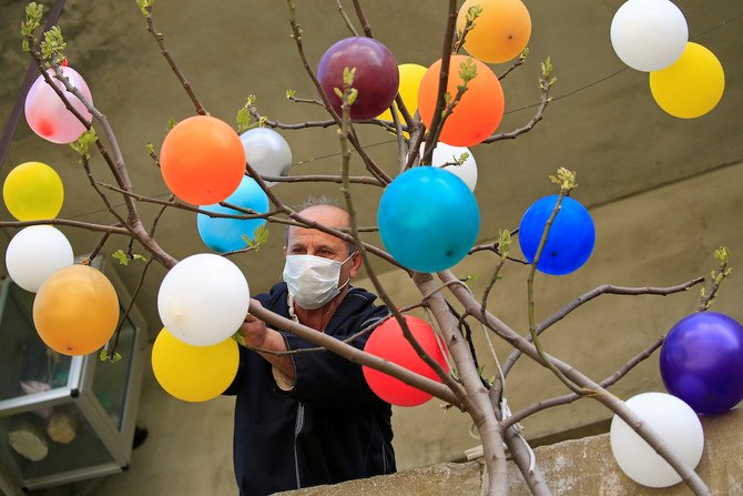 A man hangs balloons on a tree to celebrate easter during a countrywide lockdown to combat the spread of the coronavirus disease (COVID-19), in the town of Jezzine, southern Lebanon April 12, 2020. (Reuters)
