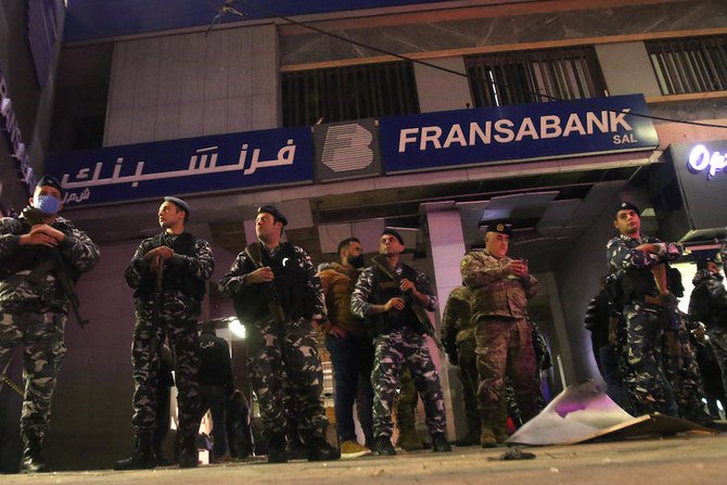 Lebanese security forces stand guard outside the entrance of a Fransabank branch in Lebanon's southern city of Sidon on April 25, 2020, after unknown assailants targeted the bank entrance with an explosive device. (AFP)