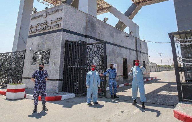 Security forces loyal Gaza's Islamist rulers Hamas, wearing personal protective equipment as a precaution against the coronavirus (COVID-19) pandemic, wait at the Rafah border crossing with Egypt, in the southern Gaza Strip on April 13, 2020, to inspect any travellers crossing into the Palestinian enclave. (AFP)