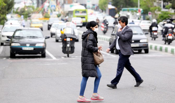 Iranians wearing protective masks cross a main road in Tehran on April 13, 2020 during the coronavirus COVID-19 pandemic. Iran said on April 14 that the number of lives lost in the country to the novel coronavirus dropped to double figures for the first time in one month. (AFP)