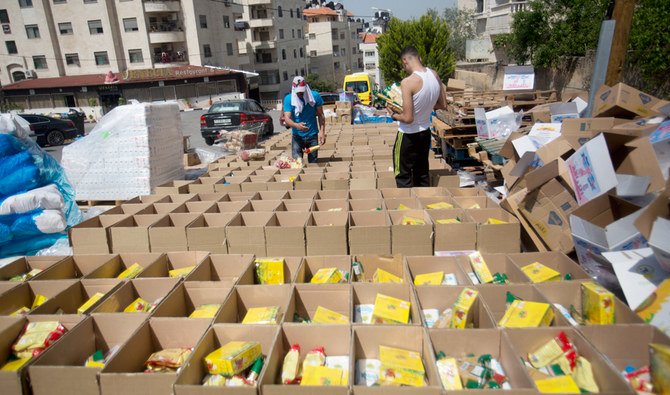 Palestinians pack boxes with food that will be distributed to poor Palestinian families ahead oof the hoy month of Ramadan, in Nablus, West Bank, Monday, April 20, 2020. (AP)