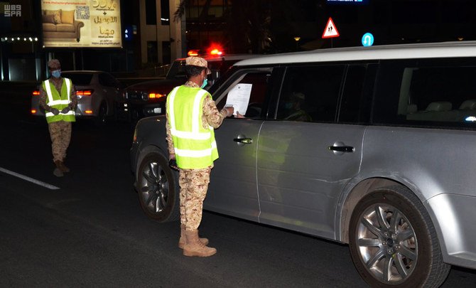 Police enforcing the curfew order check motorists along a road in Madinah on Saturday. (SPA)