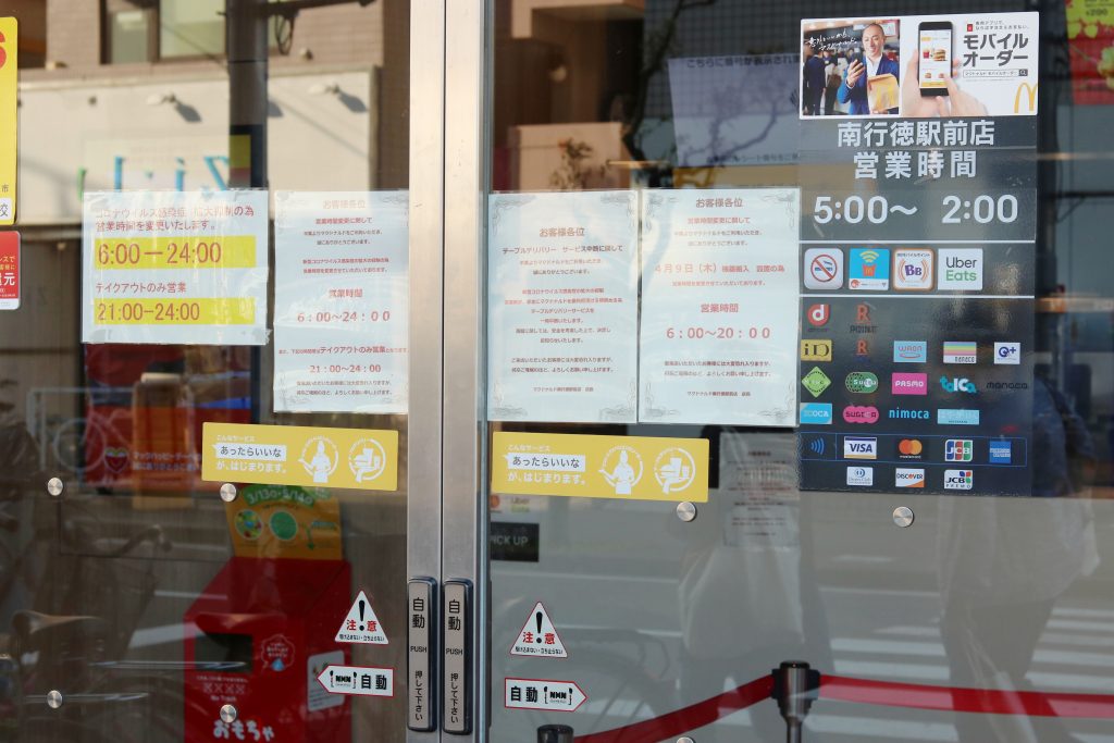Notices on the doors of McDonalds restaurant in Chiba Prefecture stating that due to the coronavirus the store's opening hours are shorter and table delivery service suspended, April. 18, 2020. (Shutterstock)