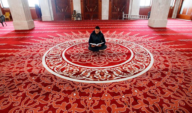 A Palestinian muezzin reads the Holy Qur’an in an almost empty mosque in Gaza City during the first Friday prayers of the holy month. (AFP)