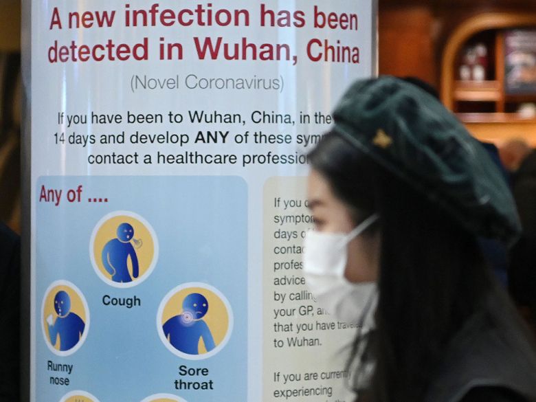 A woman passes a sign warning passengers arriving on flights into the UK about coronavirus, London Heathrow Airport, January 28, 2020. (AFP)