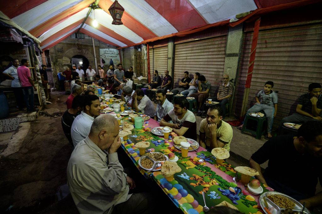 People receive a free Iftar meal as they break their fast during the Muslim holy month of Ramadan on June 11, 2018 in the Egyptian capital Cairo. (AFP)