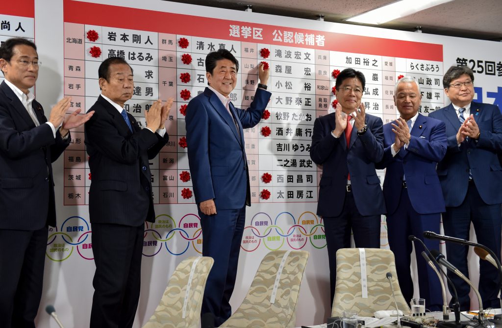 Japanese Prime Minister and ruling Liberal Democratic Party (LDP) president Shinzo Abe (3rd L) celebrates as he attaches paper flowers on the winning candidates of the Parliament's upper house election at the party's headquarters in Tokyo on July. 21, 2019. (AFP)