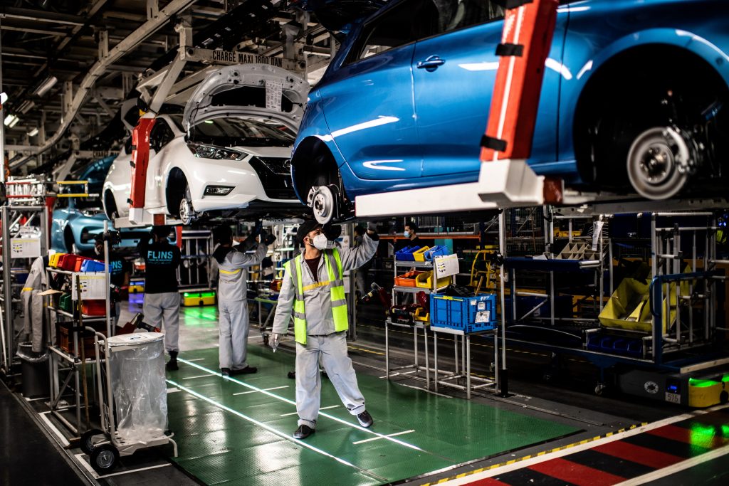 Employees wearing protective masks against the spread of the novel coronavirus, COVID-19, work along the assembly line that produces both the electric vehicle Renault Zoe and the hybrid vehicle Nissan Micra, at Flins-sur-Seine, the largest Renault production site in France, May 6. 2020. (AFP)