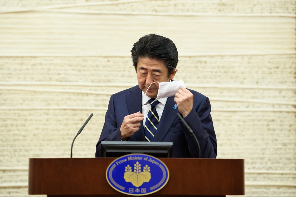 Japanese Prime Minister Shinzo Abe takes off his face mask before speaking during a press conference at the prime minister's office in Tokyo on May. 14, 2020. (AFP)