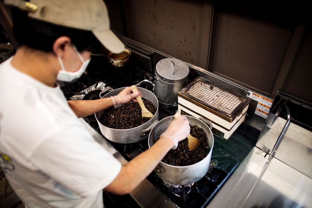 In this picture taken on May 13, 2020 Yuta Shinohara fries crickets, used as an ingredient as part of cricket ramen home-cooking kits, at a kitchen in Tokyo. (AFP)