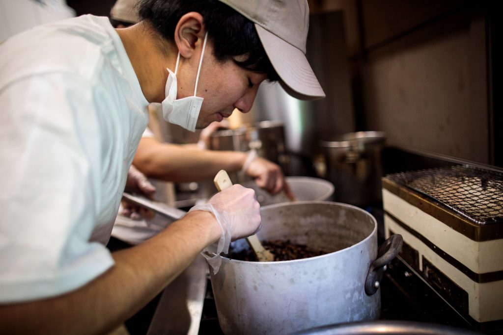 In this picture taken on May 13, 2020 Yuta Shinohara smells frying crickets, used as an ingredient as part of cricket ramen home-cooking kits, at a kitchen in Tokyo. (AFP)