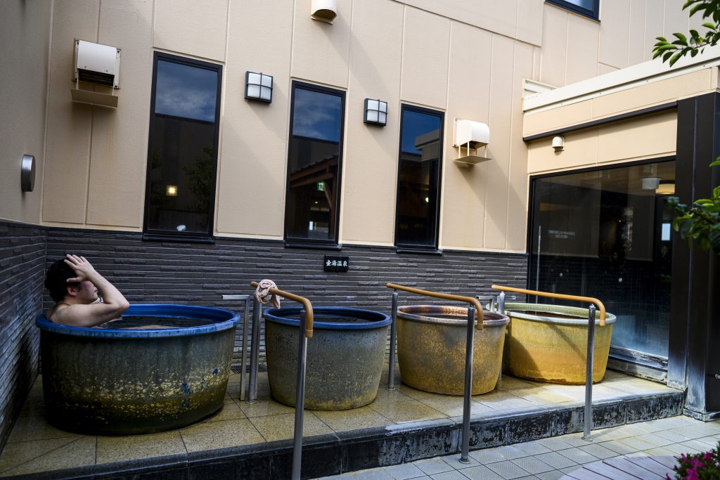In this picture taken on May 29, 2020, a man sits in a tub at a Japanese hot spring or onsen in Yokohama, Kanagawa prefecture. With the lifting of a nationwide state of emergency over the virus, Japan's onsen -- large bathhouses where patrons bathe naked in a series of warm pools and tubs -- are gradually reopening. (AFP)