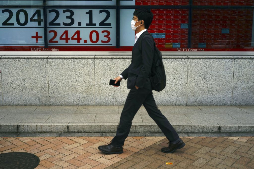 A man wearing a face mask walks past an electronic stock board showing Japan's Nikkei 225 index at a securities firm in Tokyo Monday, May 11, 2020. (File photo/AP)