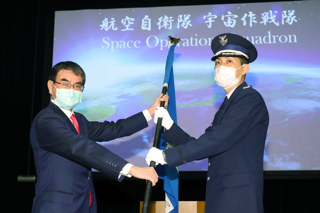 Japan Defense Minister Taro Kono, left, hands off a unit flag of the Space Operations Squadron to the head of the unit Toshihide Ashiki, right, at a launch ceremony at the Defense Ministry Monday, May 18, 2020. (File photo/Kyodo News via AP)