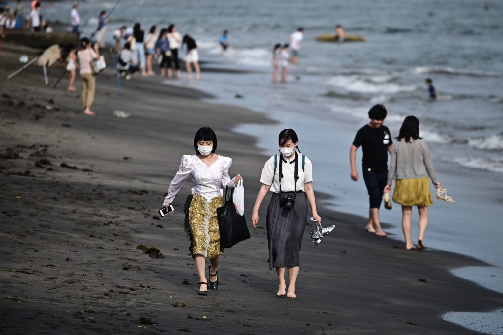 People wearing face masks gather on a beach in Kamakura in Kanagawa prefecture, southwest of Tokyo, on May. 30, 2020. (AFP)