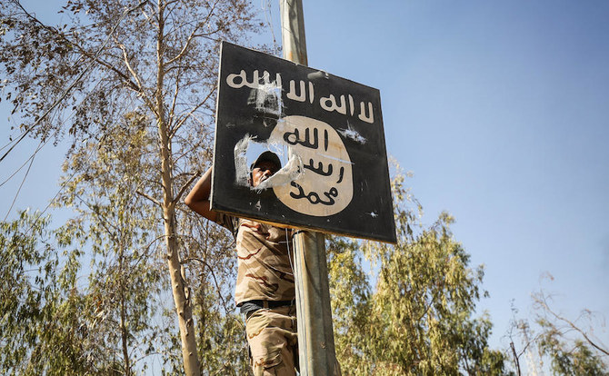 A member of Hashed Al-Shaabi (Popular Mobilization units) removes a sign on a lamp post bearing the logo of Daesh. (File/AFP)