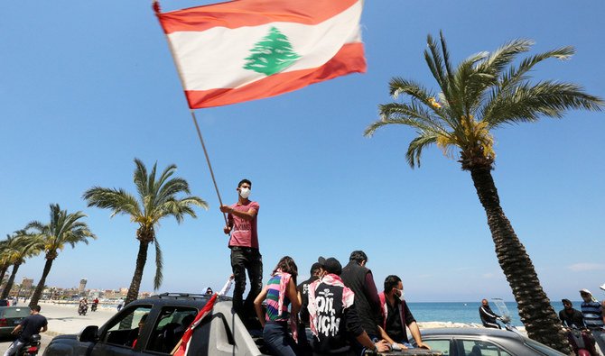 Wearing a mask for protection against COVID-19 disease, a demonstrator waves a Lebanese flag during a protest against the growing economic hardship in Tyre. (Reuters/File)