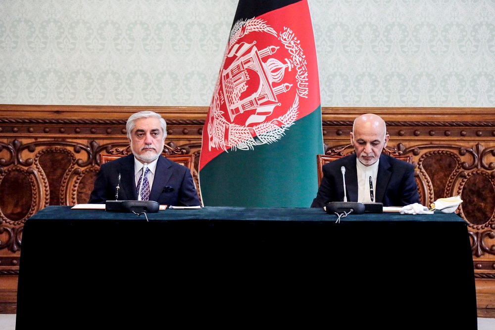 In this handout photograph taken on May 17, 2020 and released by Afghanistan's Office of Chief Executive, Afghan President Ashraf Ghani (right) and his rival Abdullah Abdullah (left) pose for photographs ahead of signing a power-sharing deal agreement at the Presidential Palace in Kabul. (AFP)
