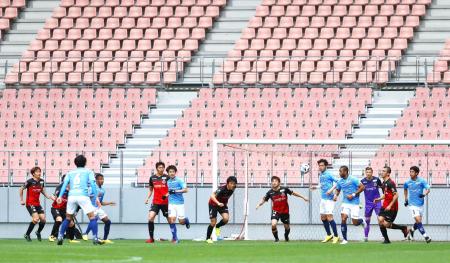 In this March 28, 2020, photo, players of Nagoya Grampus and Yokohama FC play during a practice game, without spectators following the outbreak of the new coronavirus, in Toyota, central Japan. (Kyodo News via AP)