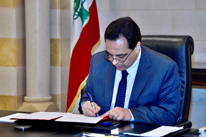 Lebanon's Prime Minister Hassan Diab signs a request for assistance from the International Monetary Fund at the government palace in Beirut, Lebanon May 1, 2020. (Reuters)