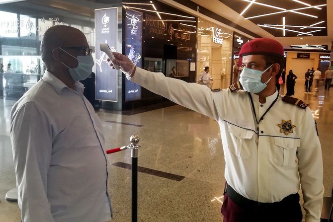A security guard checks temperature of man arriving at a shopping mall, as a screening precaution against the COVID-19 coronavirus pandemic, in the Saudi capital Riyadh on May 4, 2020, as malls reopen after authorities began a partial lifting of the coronavirus lockdown. (AFP)