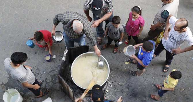 A Palestinian distributes hot wheat soup and porridge to poor residents before they break their fast in Gaza city. (AP)