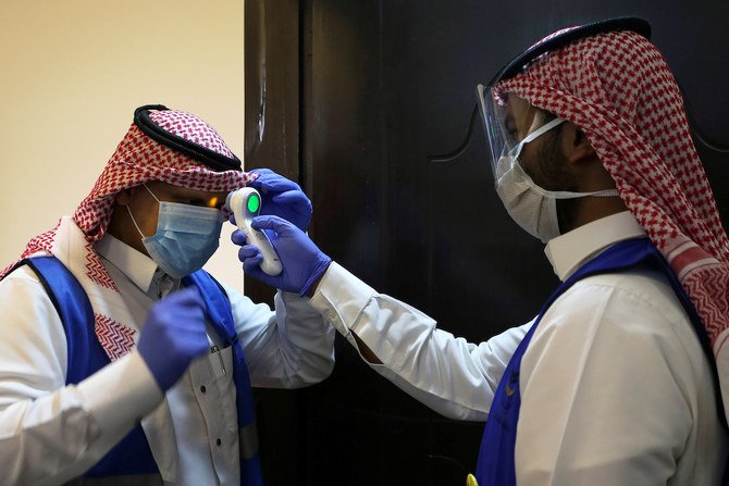 A Saudi volunteer supervisor wearing a protective face mask and gloves checks the temperature of another volunteer before preparing boxes of Iftar meals provided by a charity organisation following the outbreak of the coronavirus disease (COVID-19), during the holy month of Ramadan, in Riyadh, Saudi Arabia May 10, 2020. (Reuters)