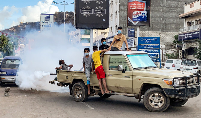 Youths wearing masks as a precaution due to COVID-19 coronavirus disease, sit in the back of a truck carrying out a fumigation in an area in Yemen's southern coastal city of Aden on May 5, 2020, as part of a campaign to prevent the spread of insect-borne diseases such as malaria, dengue fever, and Chikungunya virus amidst the novel coronavirus pandemic. (AFP)