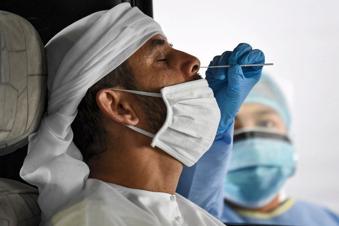 A medical staffer obtains a swab sample from a man inside a vehicle at a drive-through COVID-19 coronavirus testing centre in al-Khawaneej of Dubai. (AFP)