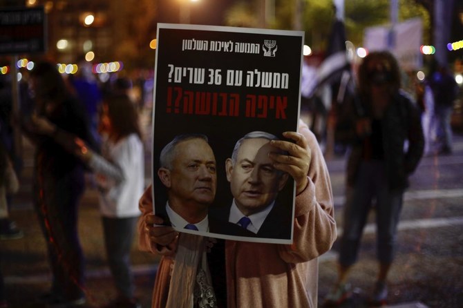 A woman holds a poster of Israeli Prime Minister Benjamin Netanyahu, right, and Benny Gantz, left, that read ‘a government with 36 ministers? Where is the shame?’ during a protest against the government and the corruption, at Rabin square, in Tel Aviv, Israel, Saturday, May 2, 2020. (AP/Ariel Schalit)