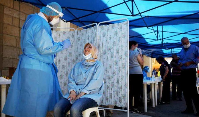 A woman gets ready to be tested for the coronavirus by a nurse with the mobile crew of the Lebanese American University Medical Center, in the town of Jezzine. (AFP)