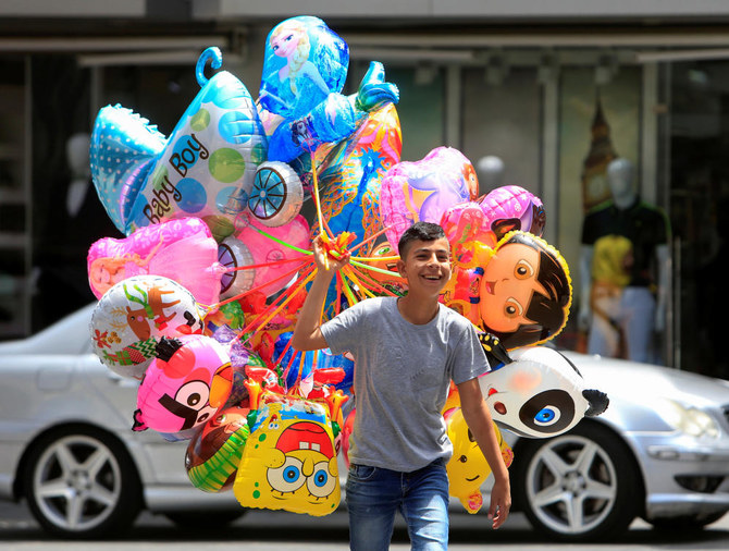 A boy walks as he holds balloons for sale, ahead of the Eid Al-Fitr holiday marking the end of Ramadan, amid concerns over the spread of the coronavirus disease, in Sidon, Lebanon on May 23, 2020. (Reuters)