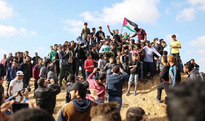 Palestinian protestors waves their national flag during a demonstration commemorating Land Day, near the border with Israel, east of Gaza City, on March 30, 2018. (AFP)