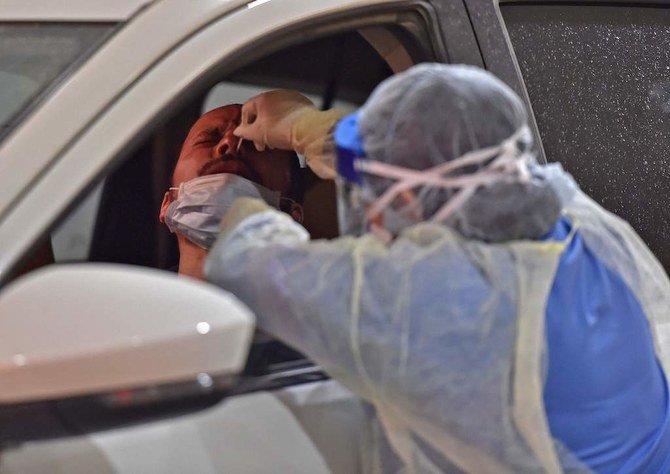 Health workers perform nose swab tests during a drive through coronavirus test campaign held in Diriyah hospital in the Saudi capital Riyadh on May 7, 2020 amid the COVID-19 pandemic. (AFP)