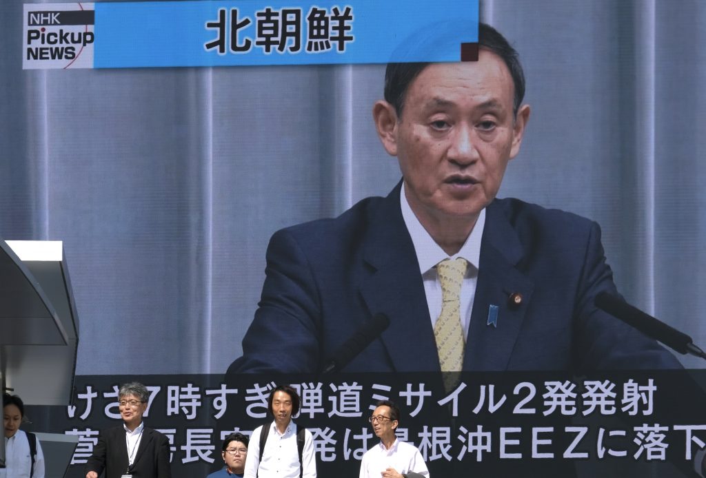 Pedestrians walk past a screen in Tokyo showing Japan's Chief Cabinet Secretary Yoshihide Suga, reporting about North Korea's missile launch into the sea on October 2, 2019. (AFP)