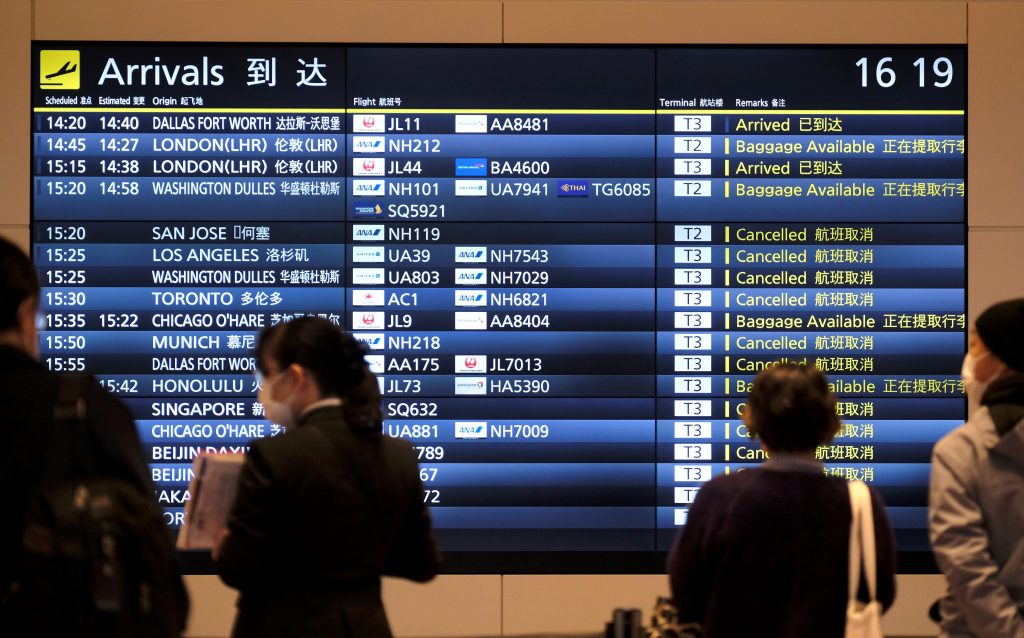 A signboard with noticeable cancellations is displayed at an arrival floor of the Tokyo's Haneda Airport International Terminal, March 30, 2020. (AFP)
