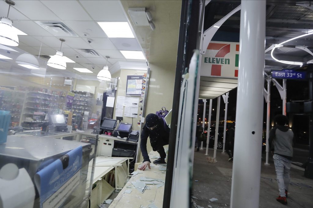 A person enters through a window of a 7-Eleven to carry merchandise from the store, June. 1, 2020, in New York. (File photo/AP)