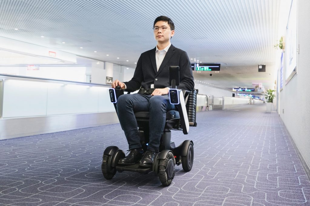 This photo provided by WHILL, Inc., shows the trial of the company's Autonomous Drive System at Haneda Airport in Tokyo in November, 2019. The autonomous mobility system, which works like a wheelchair without anyone pushing it, is scuttling around a Tokyo airport to help with social distancing amid the coronavirus pandemic. (WHILL, Inc. via AP)