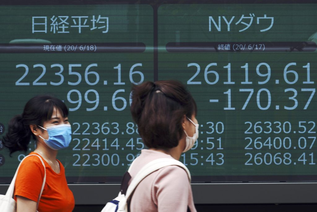 Women walk past an electronic stock board showing Japan's Nikkei 225 and New York Dow indexes at a securities firm in Tokyo, June. 18, 2020. (File photo/AP)