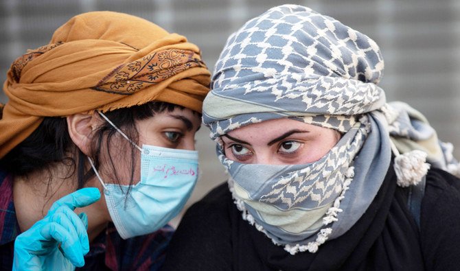 A mask-clad young Iraqi woman speaks to another during an anti-government demonstration in the southern Iraqi city of Basra, despite the ongoing threat of the novel coronavirus. (AFP)