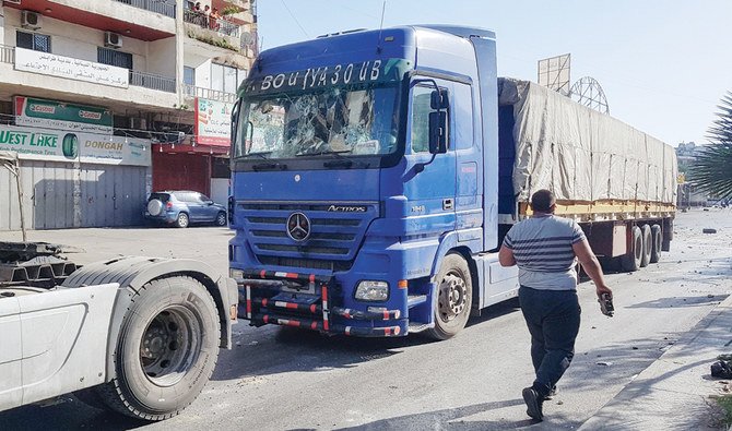 A Lebanese man walks past a truck which was damaged following clashes between protesters and the army in the port city of Tripoli. (AFP)